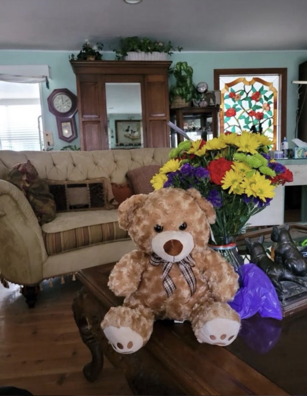A teddy bear and a bouquet of fresh flowers delivered to a recipient's living room